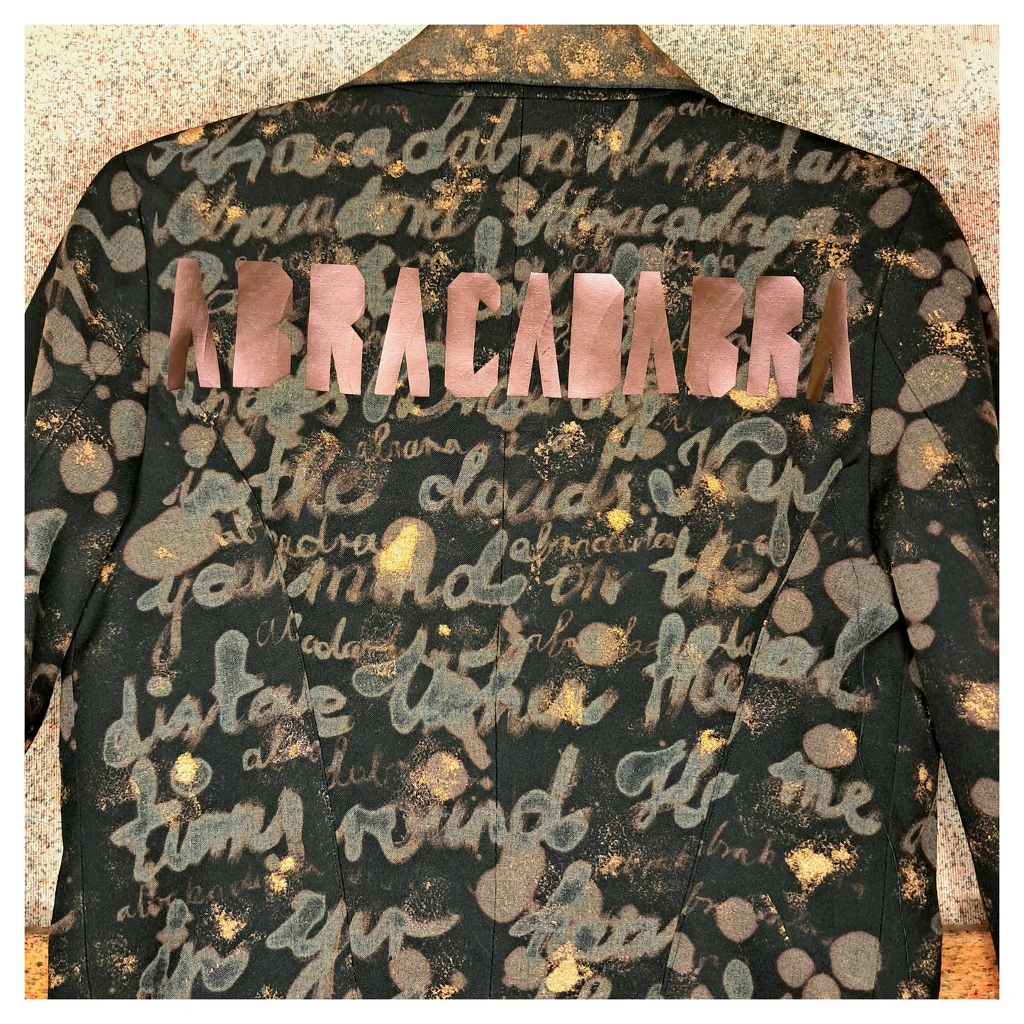 Recycled, upcycled tie-dye black and bronze blazer. Lady Gaga’s Abracadabra lyrics hand-painted, tailcoat-style with black ruffle trim.