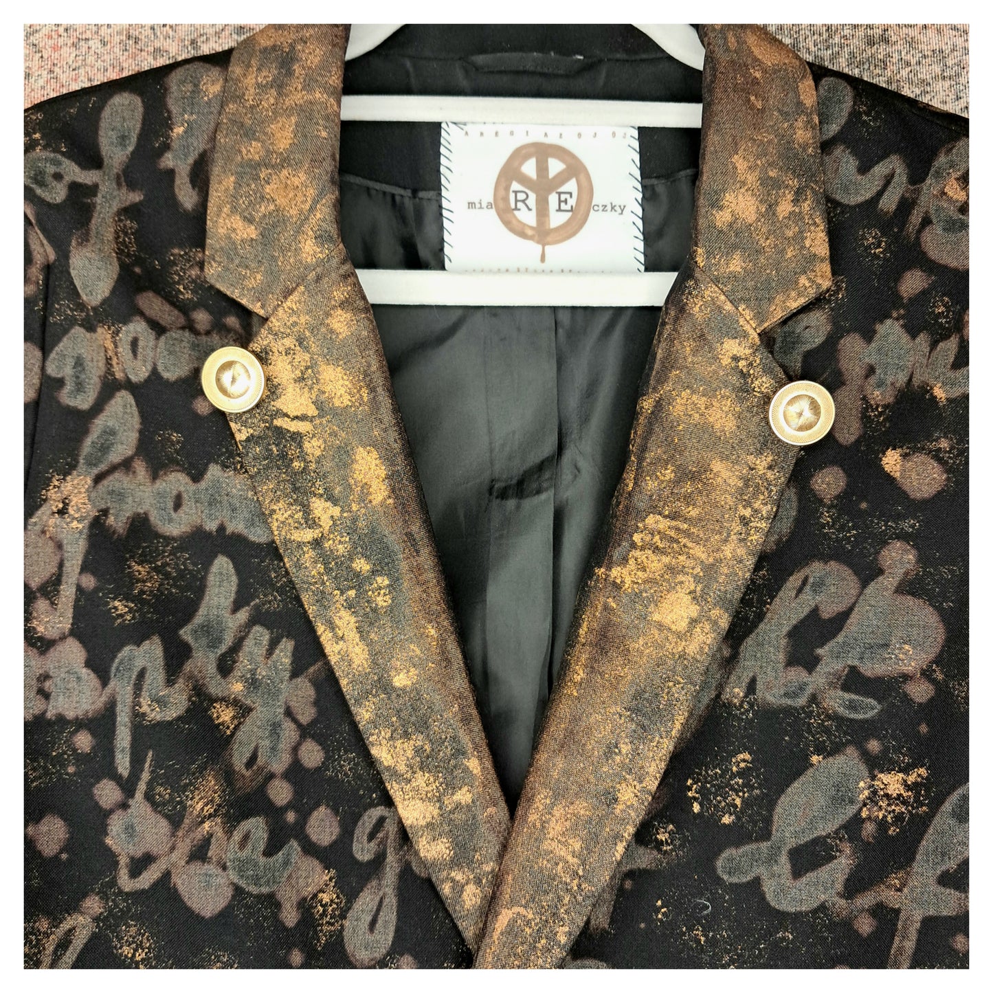 Recycled, upcycled tie-dye black and bronze blazer. Lady Gaga’s Abracadabra lyrics hand-painted, tailcoat-style with black ruffle trim.