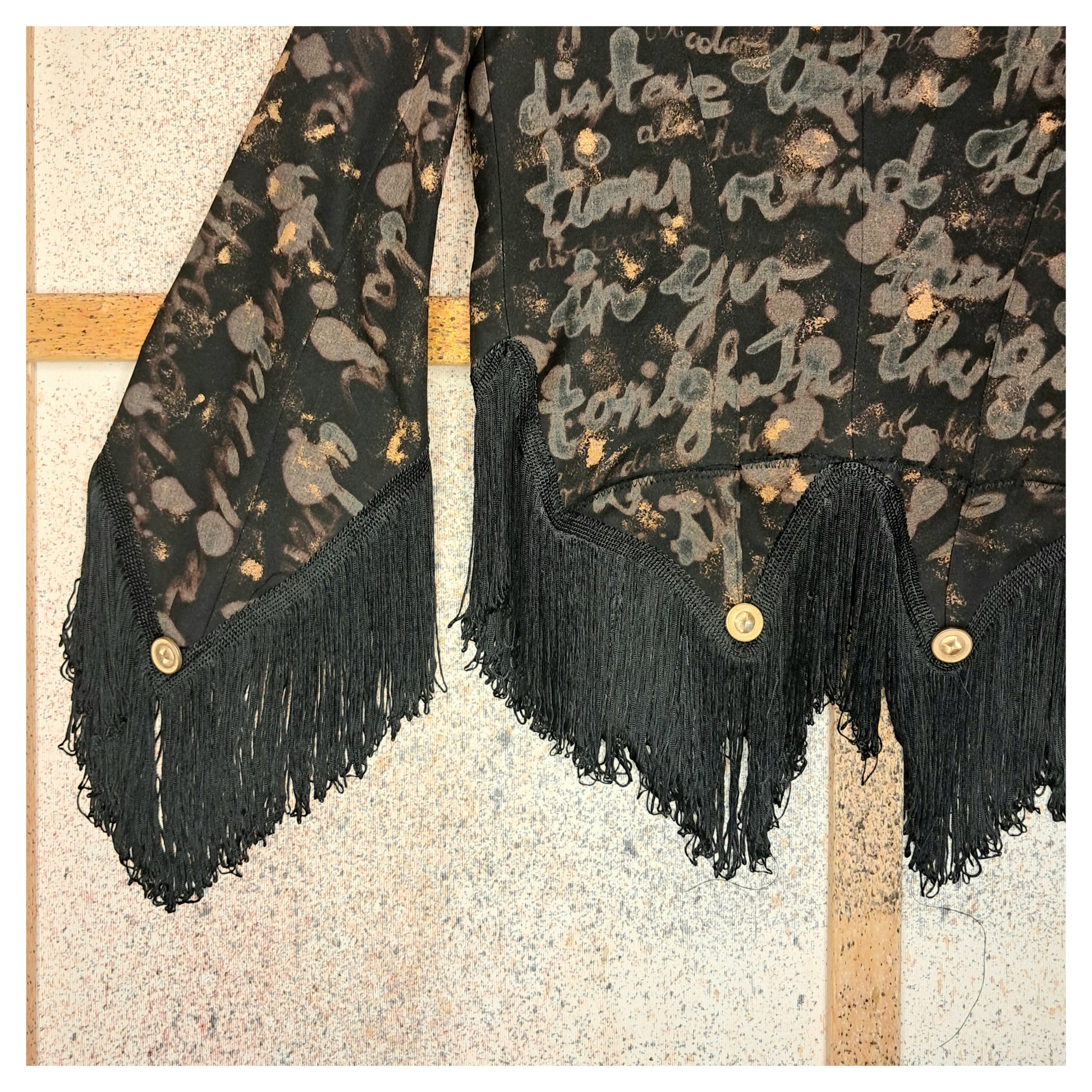 Recycled, upcycled tie-dye black and bronze blazer. Lady Gaga’s Abracadabra lyrics hand-painted, tailcoat-style with black ruffle trim.