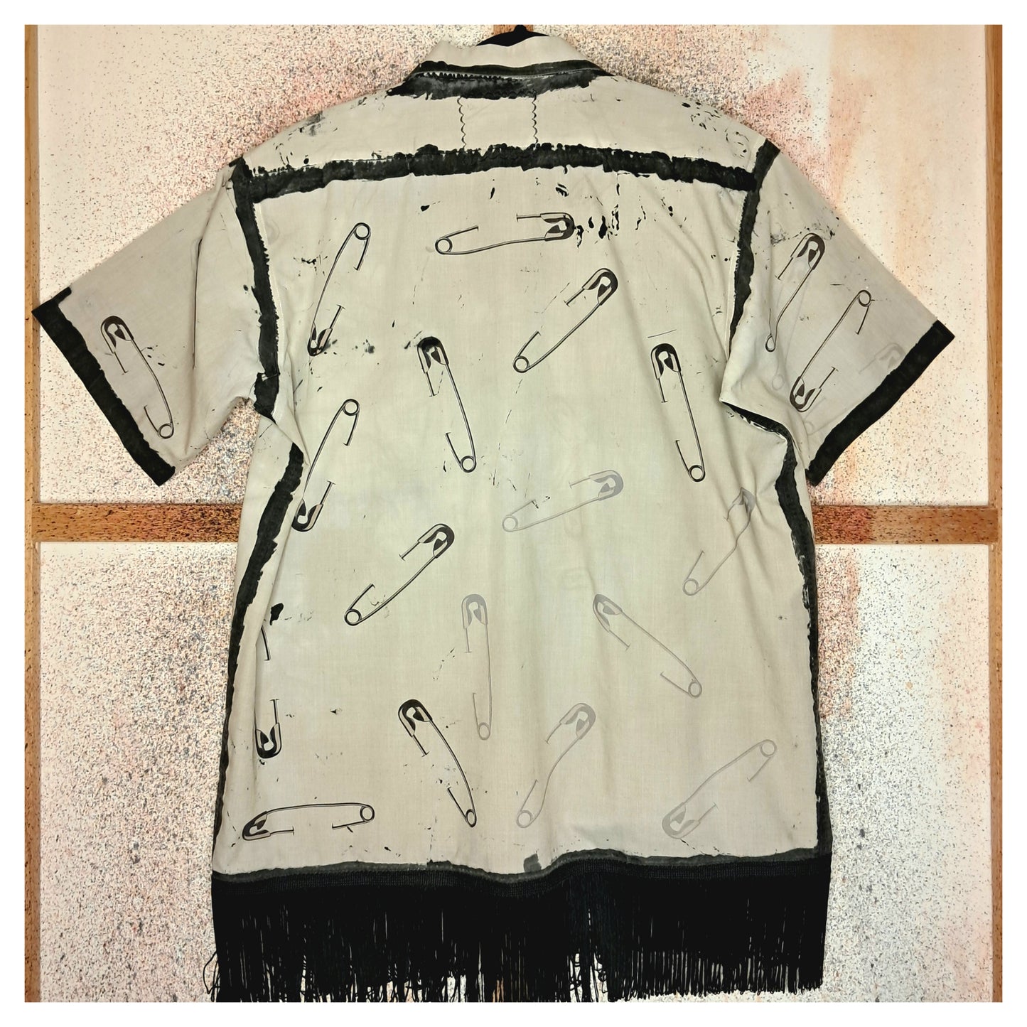 Recycled, upcycled punk beige short-sleeve shirt with safety pin pattern. Handpainted with black fringe and vintage buttons