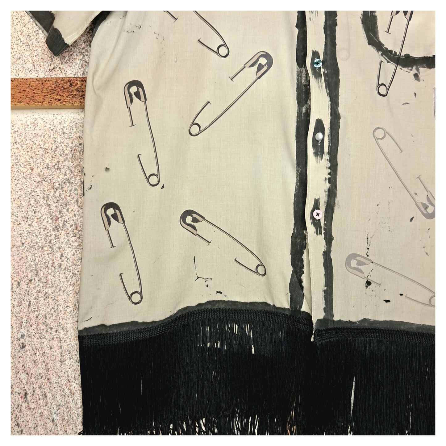 Recycled, upcycled punk beige short-sleeve shirt with safety pin pattern. Handpainted with black fringe and vintage buttons